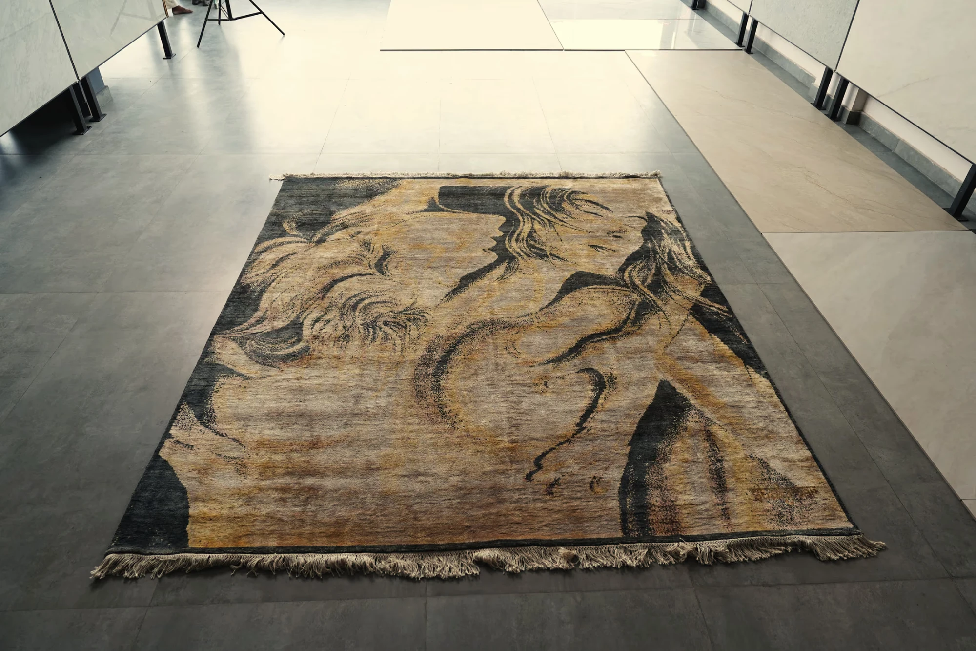 Khwaab, the hand-knotted silk rug, lying on a stone floor in the showroom